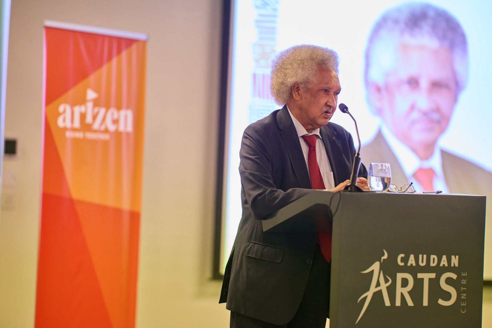 Guest speaker presenting beside the Arizen banner