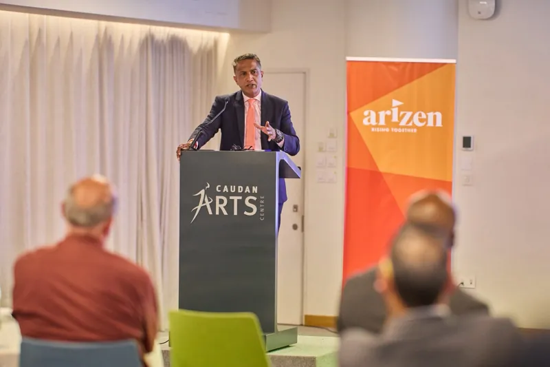 A speaker at the Caudan Arts Centre podium beside the Arizen banner